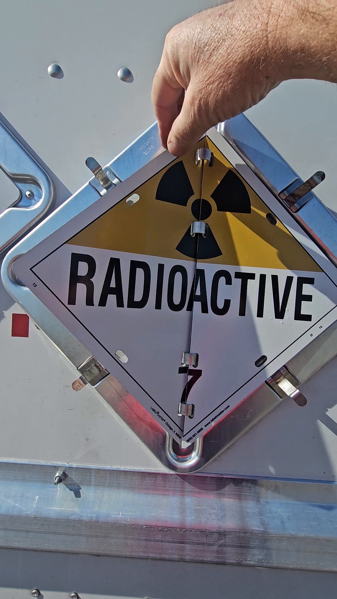 A driver holding up a RADIOACTIVE placard, deciding which placard is correct for the load